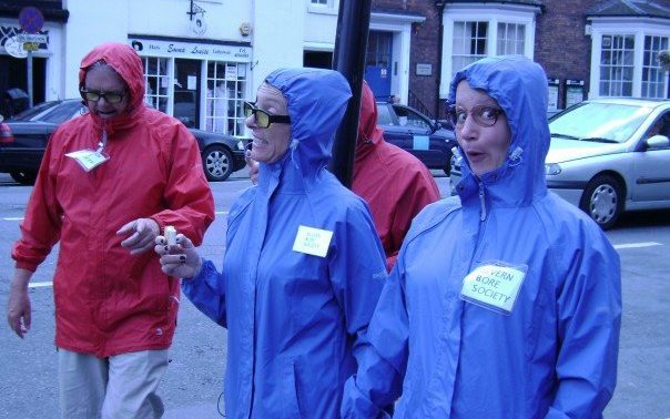 We see 4 people wearing rain macs with the hoods up and glasses. They are walking down the road and appear to be talking. These are the Severn Bores who like to tell people the facts and figures of the Severn bore wave.
